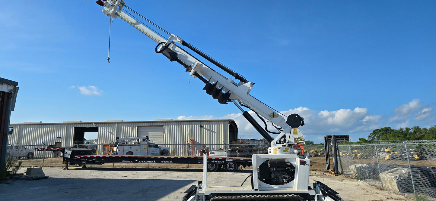 EZ Hauler 55M mobile lift crane with blue and white boom, radio remote and pin-on bucket parked at construction site with warehouse in background.