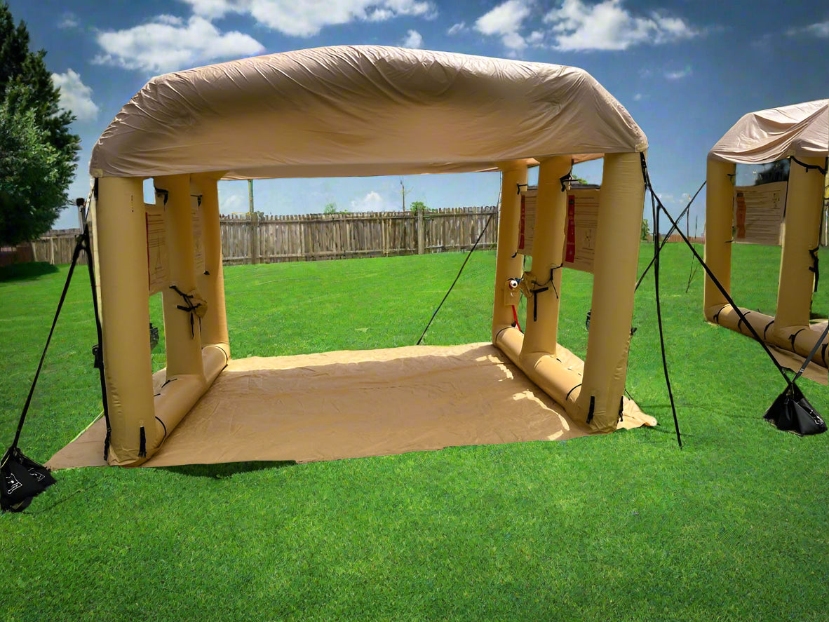 Tan inflatable LAMS L-10 air shelter with arched roof and open sides set up on a grassy field.