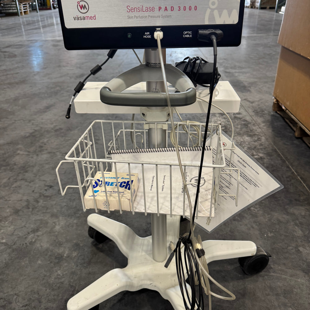 
                  
                    Vasamed SensiLase PAD 3000 skin perfusion unit on wheeled stand with digital display and cables in warehouse.
                  
                