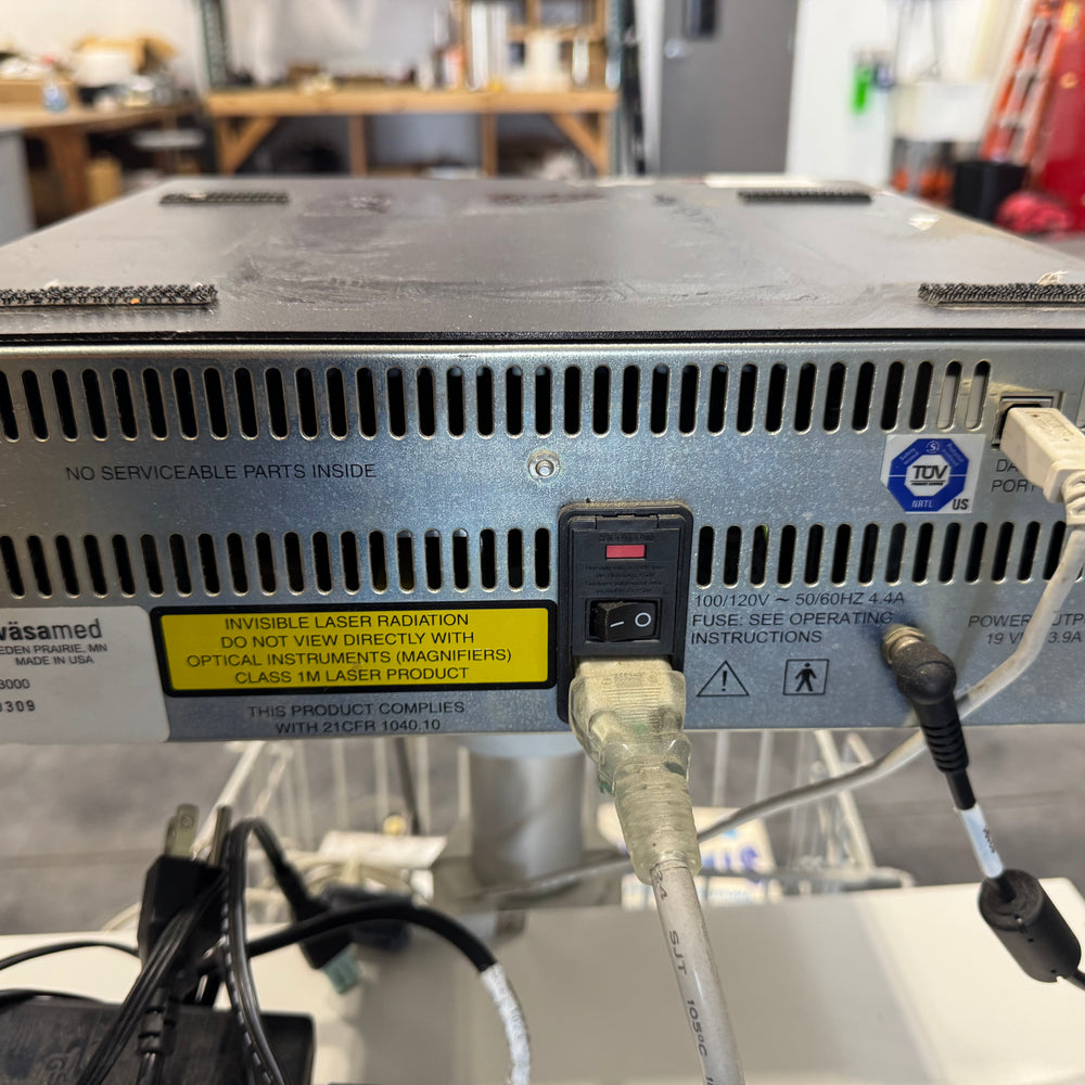 
                  
                    Rear view of Vasamed SensiLase PAD 3000 device showing ventilation slots, labels, and connected cables on equipment cart.
                  
                