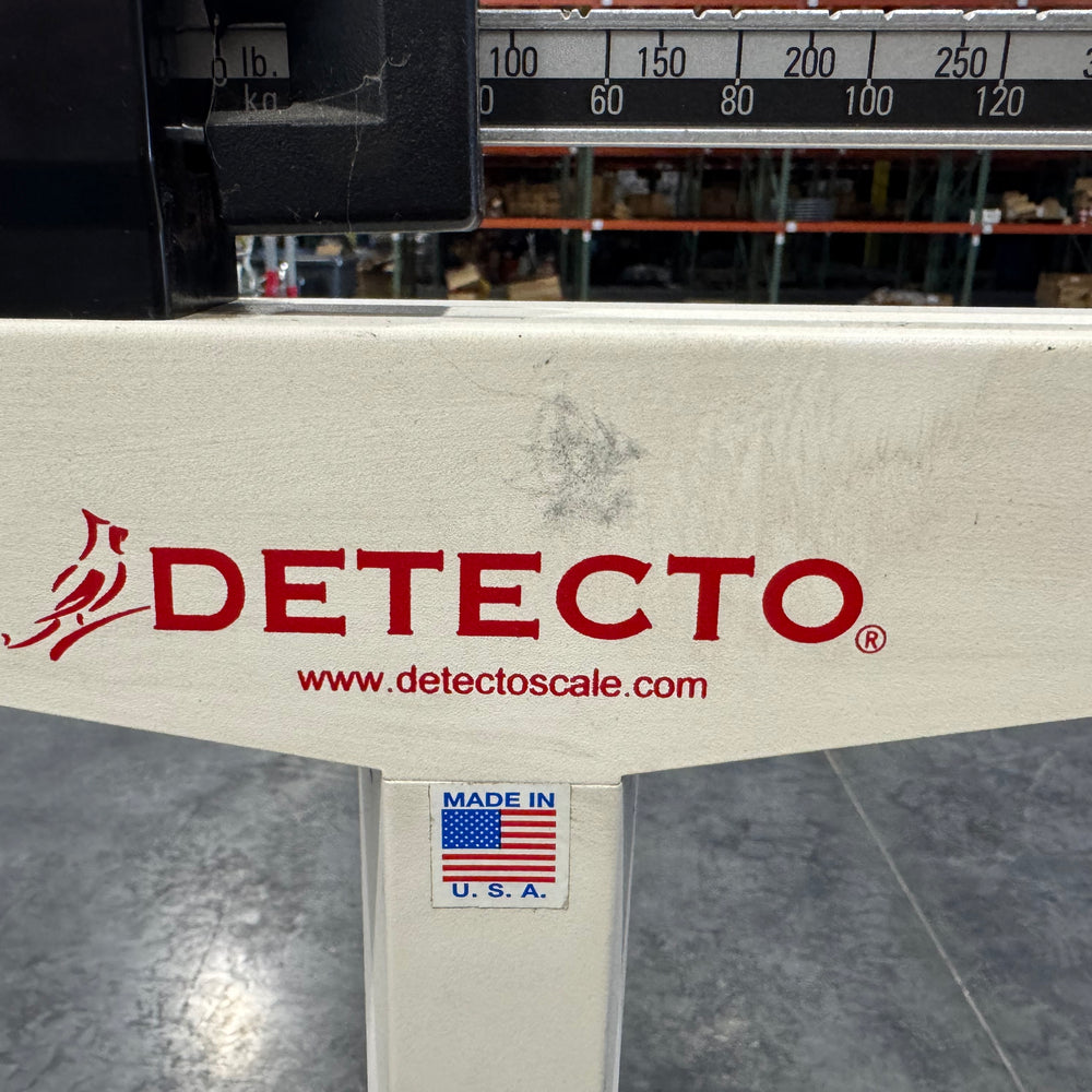 Detecto Eye-Level Physician Scale base showing red branding and measurement beam.